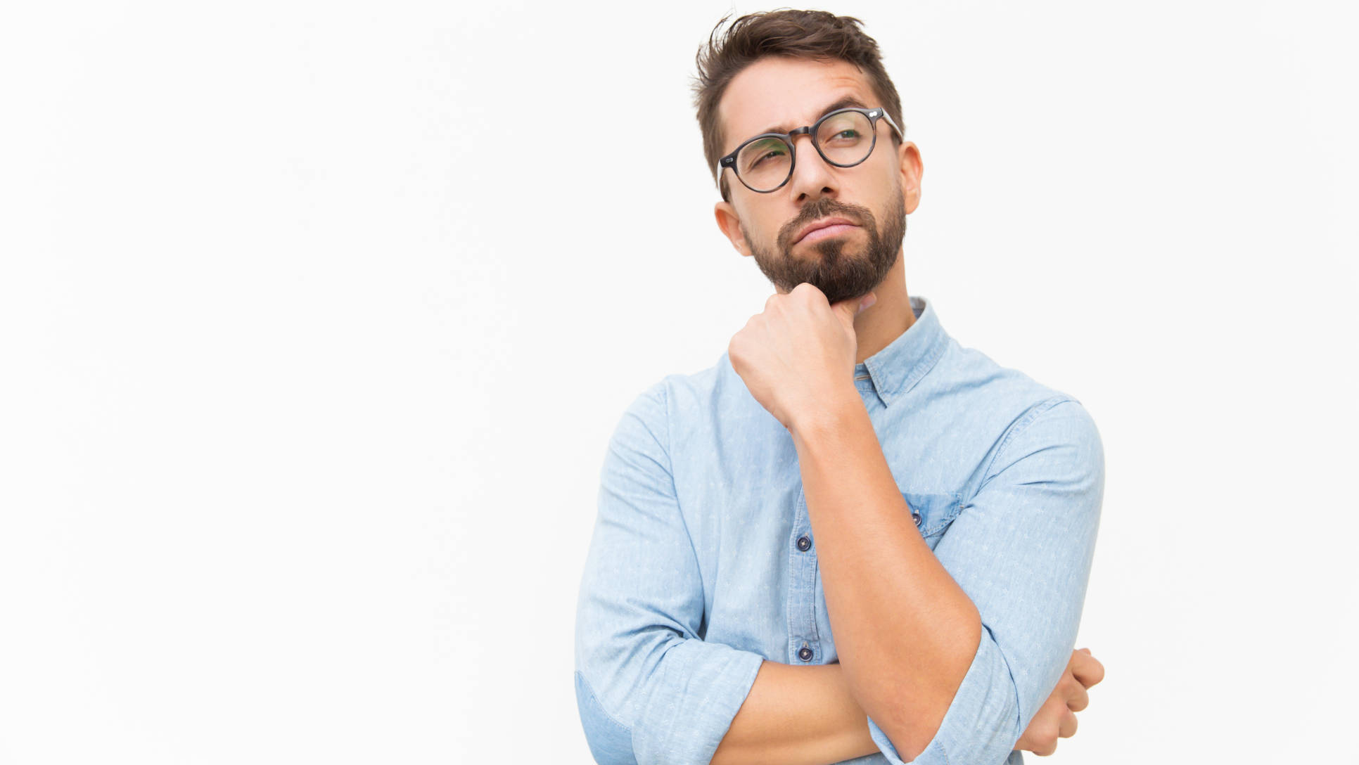 Pensive male customer looking away at copy space, touching chin, thinking. Handsome young man in casual shirt and glasses standing isolated over white background. Advertising concept