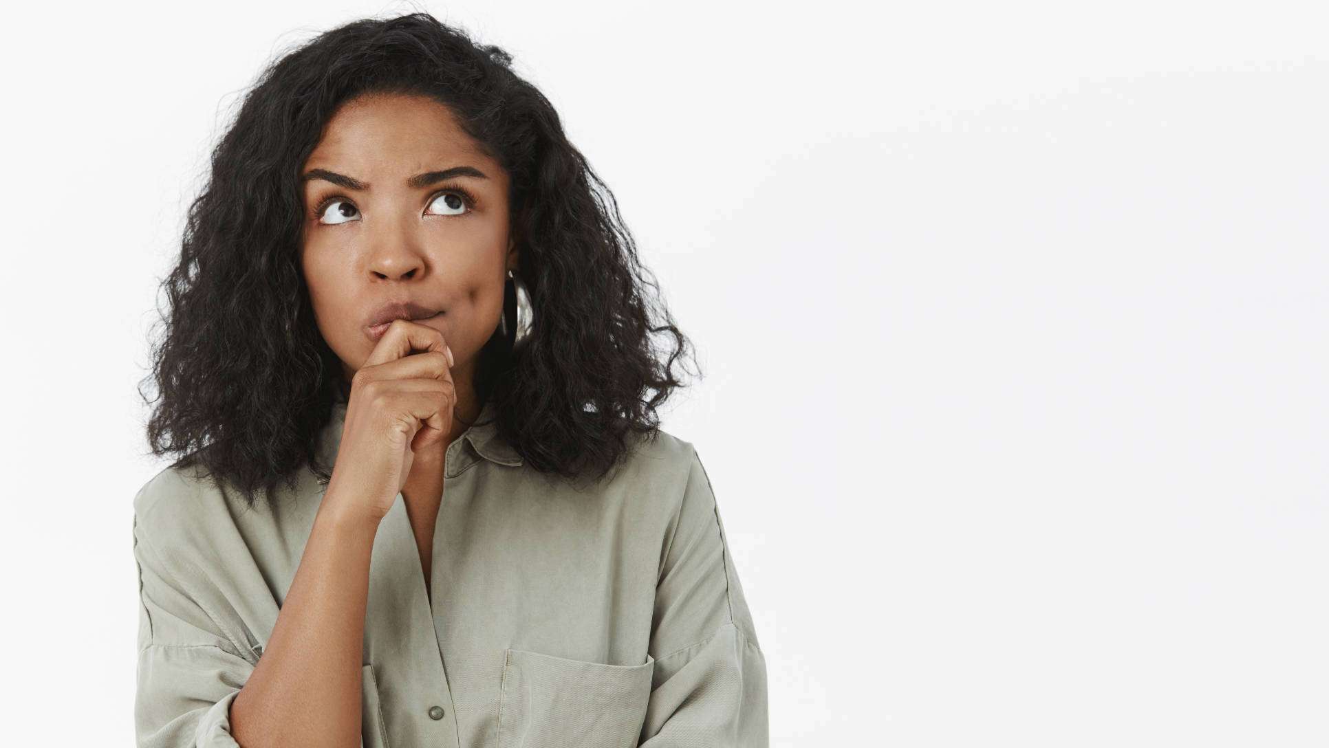 Girl needs make up excuse thinking standing focused in thoughtful pose holding hand on chin frowning looking up posing over gray background determined and concentrated on thought. Copy space