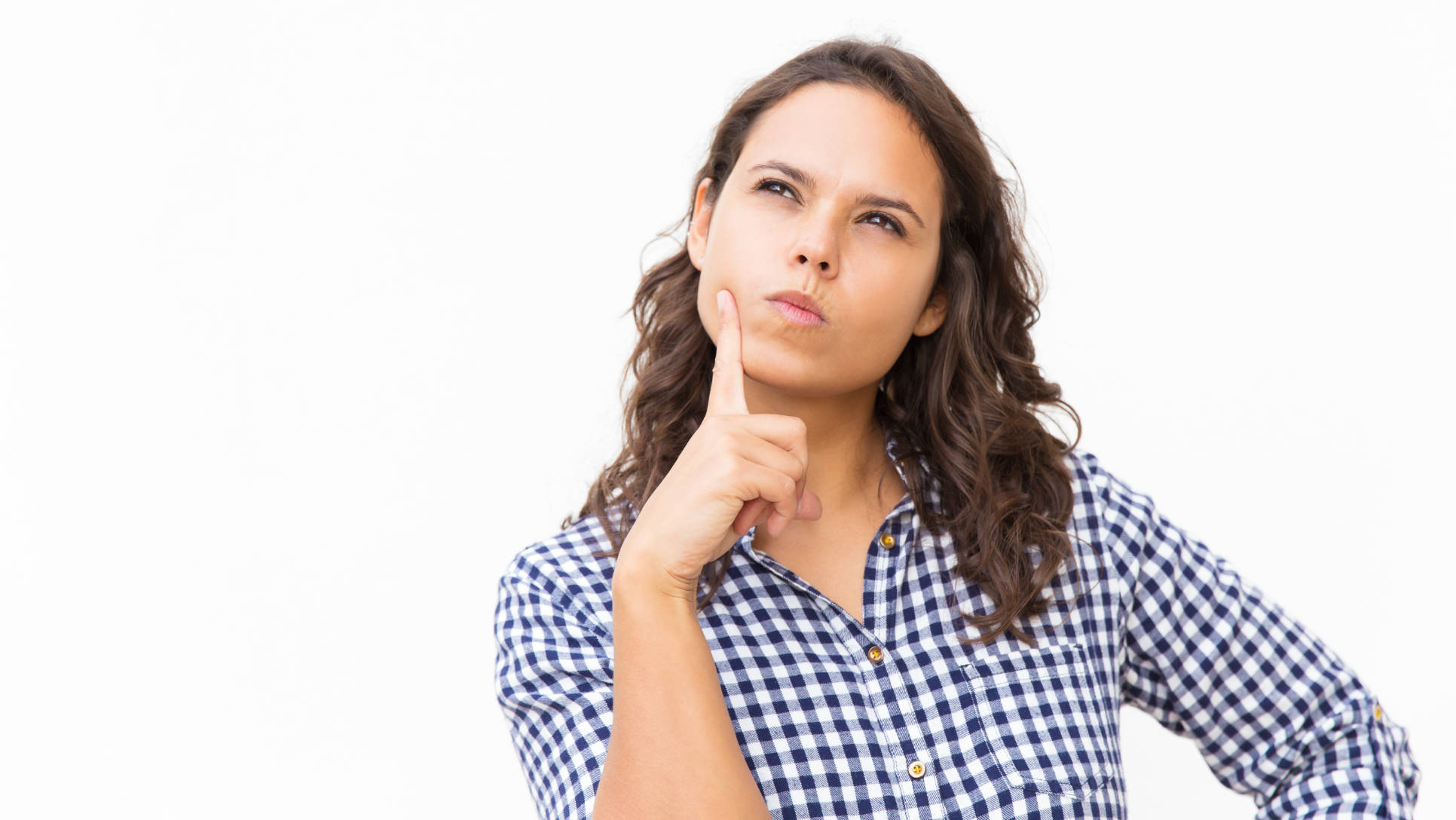 Pensive female customer touching face and thinking hard. Young woman in casual checked shirt standing isolated over white background. Decision making or advertising concept